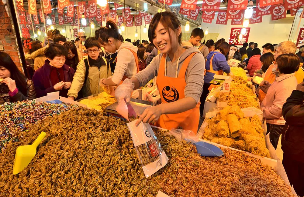 woman scooping dried squid at Taiwan food market. Image: Intrepid Travel