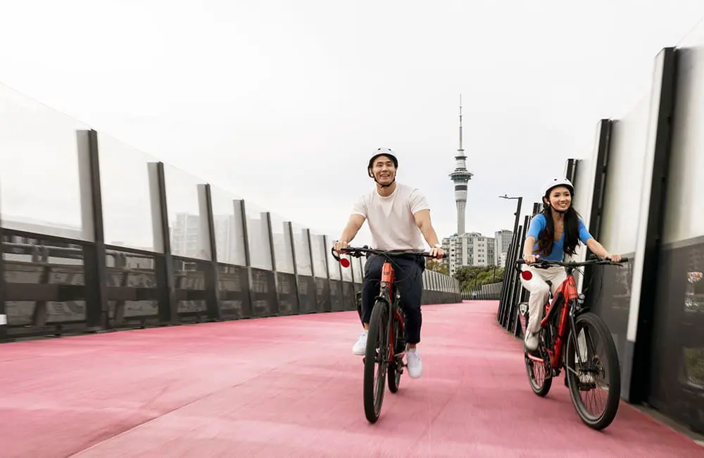 Couple cycling over bridge on Auckland's Nelson Street Cycleway – Tourism New Zealand Active Escapes campaign. Image: Miles Holden