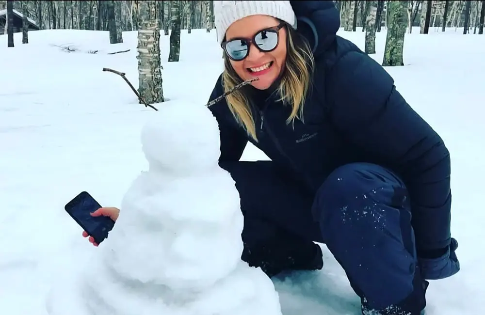 Amy Mude with snowman in snow.