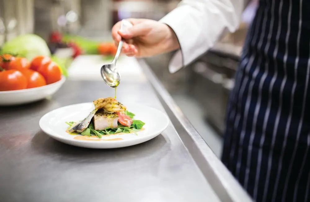 Chef plating up a dish on board kitchen on The Ghan.