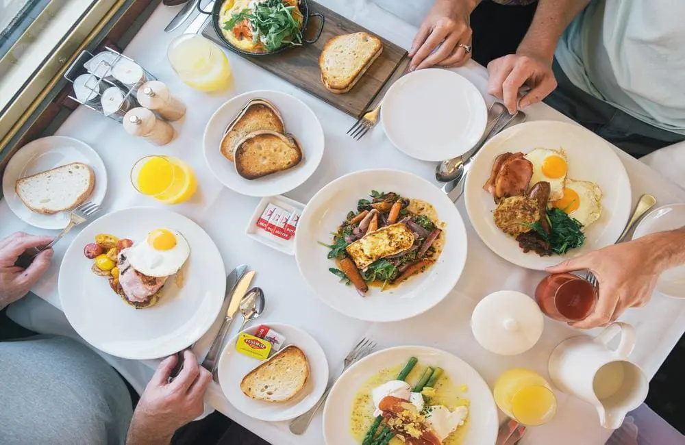 Top-down image of breakfast dishes with hands on The Ghan rail journey.