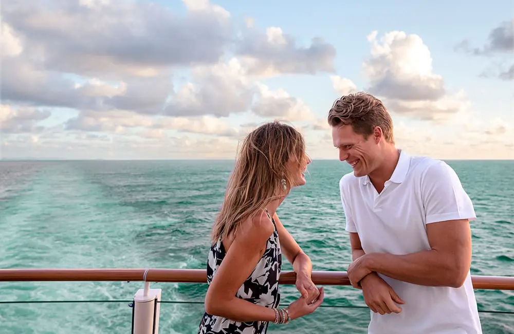 happy couple leaning on rail on Norwegian Cruise Line ship at sea – NCL Just Cruise fare intro