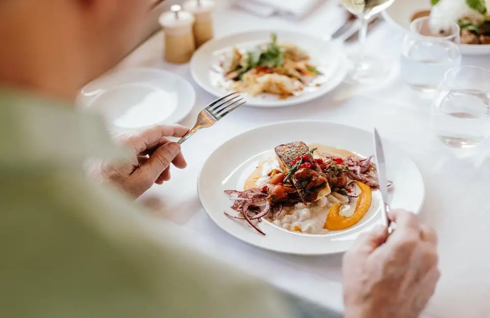 Journey Beyond passenger with main meal on board a rail journey on The Ghan.