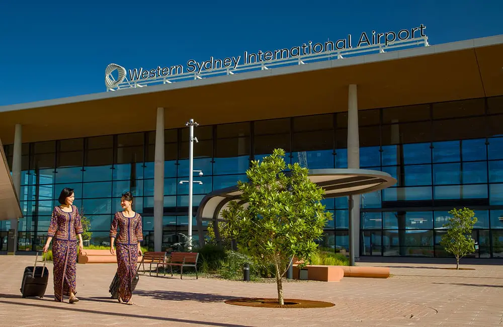 Singapore Airlines flight crew members walking in front of the Western Sydney International Airport terminal (WSI)