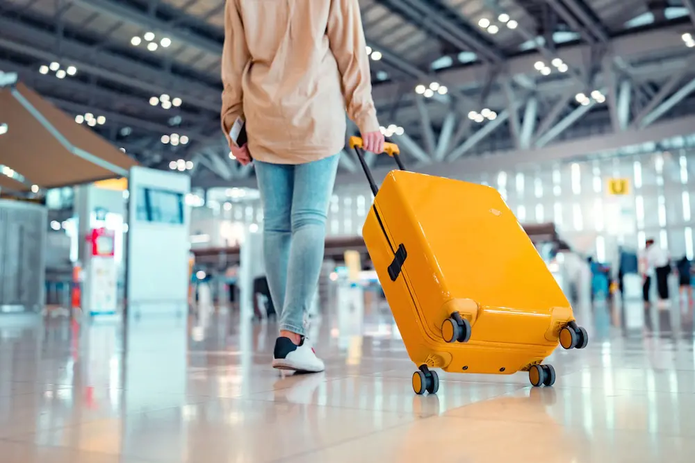 International travel jumps 20% since 2019; huge rises for China & Vietnam, but Thailand sees big drop 2 Young female traveler passenger walking with a yellow suitcase at the modern Airport Terminal, Back view of woman on her way to flight boarding gate, Ready for travel or vacation journey