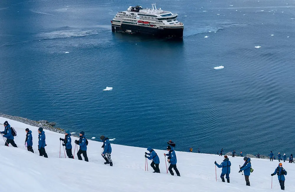 HX Expeditions passengers Walking in Orne Harbour, Antarctica with ship in background. Image: Kay Fochtmann