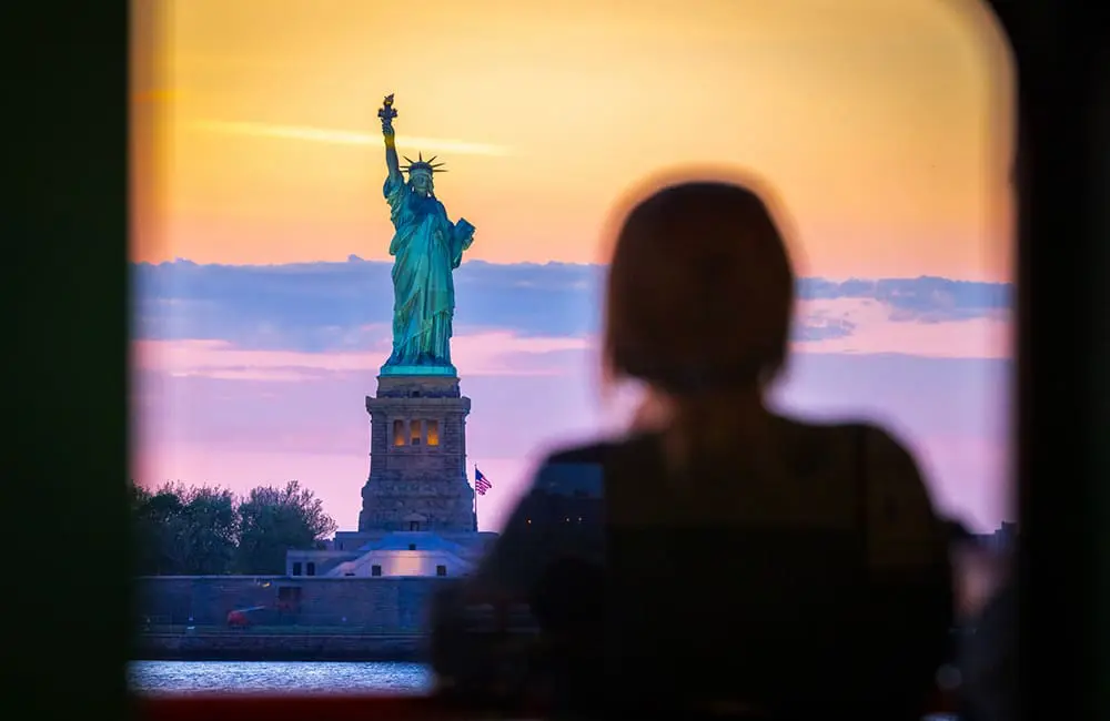 Female traveller looking at the Statue of Liberty in NYC from Staten Island Ferry. Image: cmart7327/Stock
