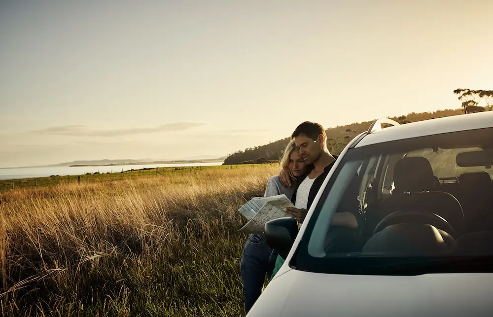 Easter travel dips under fuel pressure, yet hope grows as relief kicks in 1 Shot of a cheerful young couple reading a map together while standing next to a open road with their car outside during the day