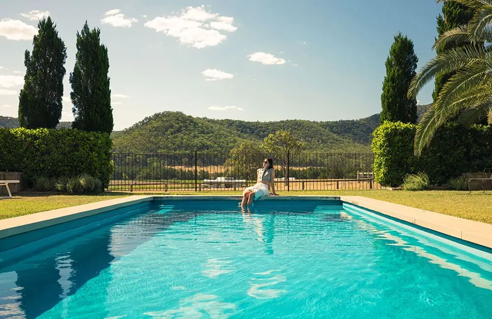 Woman enjoys the sun by the pool at Krinklewood Estate in Broke. Image: Destination NSW