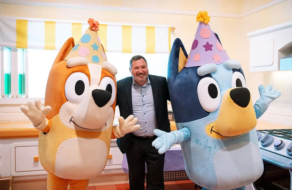 Queensland Environment & Tourism Minister Andrew Powell with Bluey characters Bingo and Bluey.