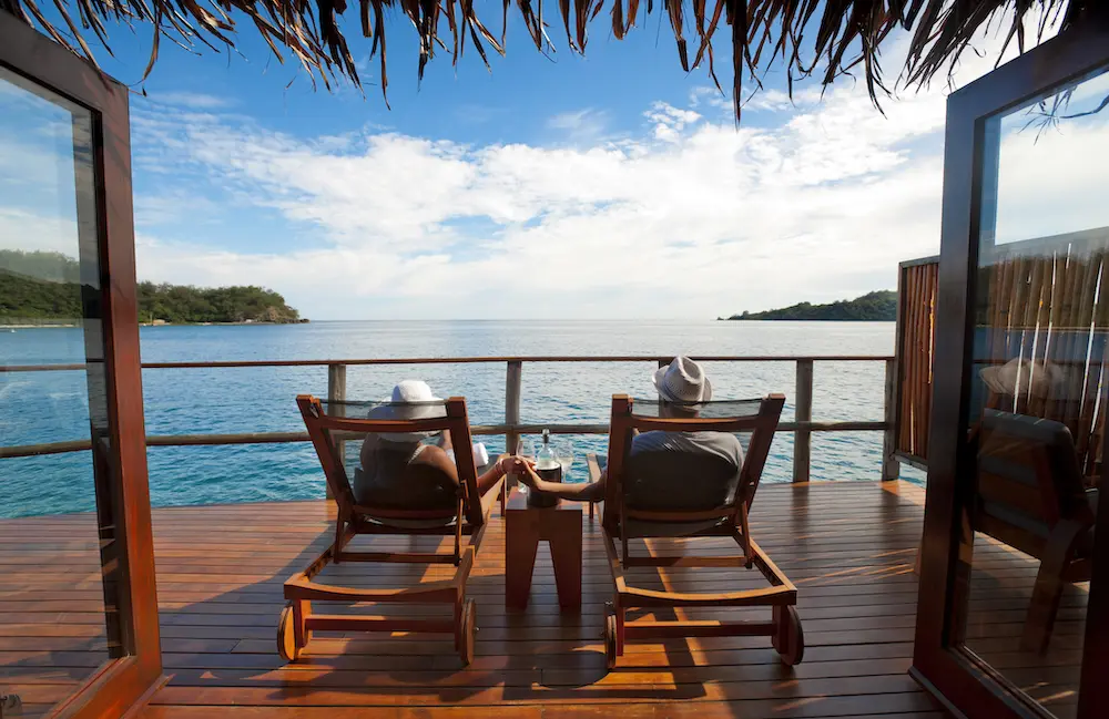 Couple relaxing on sun lounges in an over water bungalow