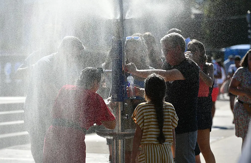 People seek relief from Europe's extreme heatwave at a public water dispenser in Paris. Image: Olivier DJIANN/iStock