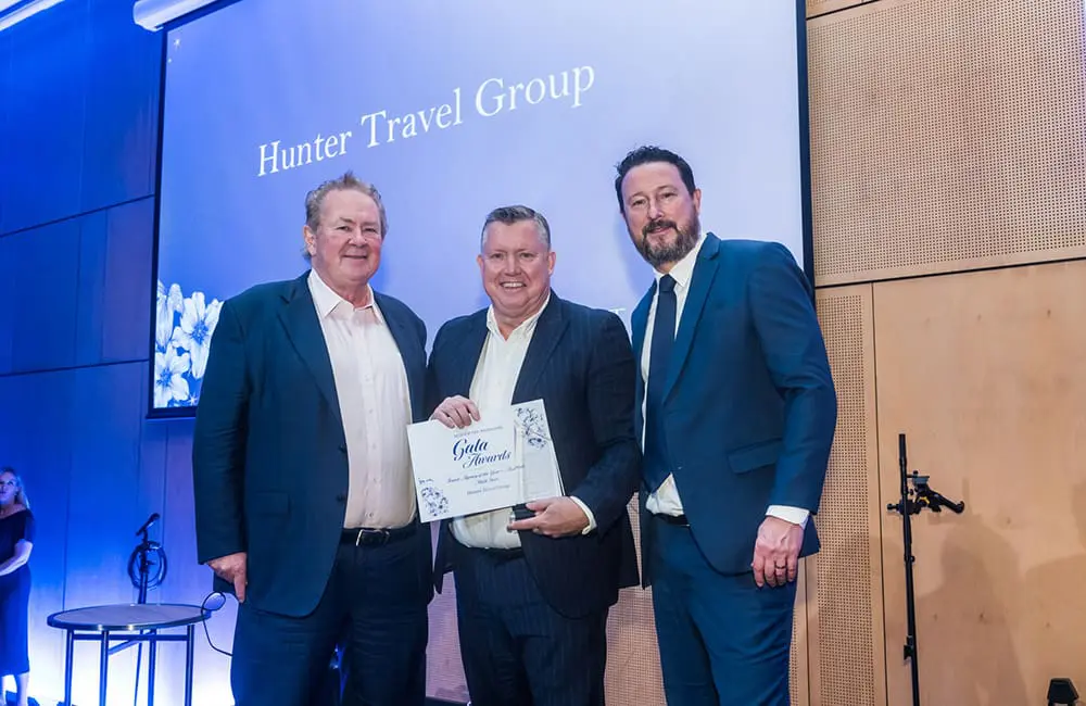 A Newcastle agency group just took out Helloworld's top national title for 2026 1 Helloworld Travel CEO & MD Andrew Burnes, HTG CEO Brett Dann and Helloworld Travel Group GM Retail Networks Nick Sutherland at the gala awards in Cairns.