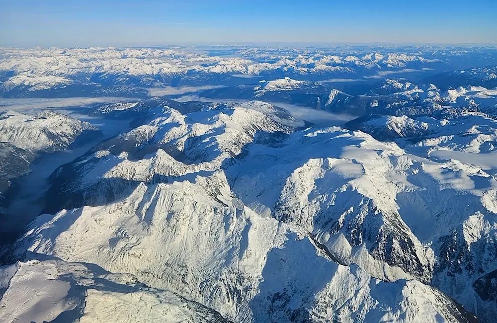 Canada’s scale is hard to grasp until you see it from above, where snow-covered peaks stretch far beyond a single itinerary. Image: Teagan Gunter