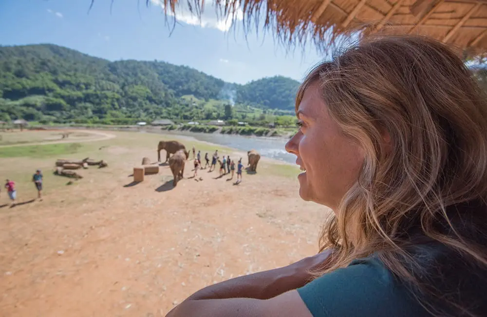 Female traveller observes Asian elephants at sanctuary in Thailand – Intrepid Travel elephant tourism campaign 2026