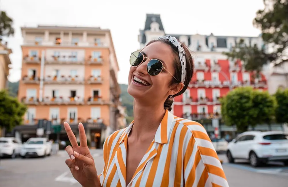 One in four young Aussies heading to Europe "no matter what", new data shows 1 Young female traveller throws the peace sign in Italy street – Europe trip in 2026. Image: MStudioImages/iStock