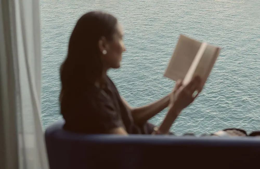 Wake up somewhere extraordinary: Oceania Cruises launches new collection with 50% reduced deposits 2 Female traveller reading book in library with ocean view aboard Oceania Allura cruise ship
