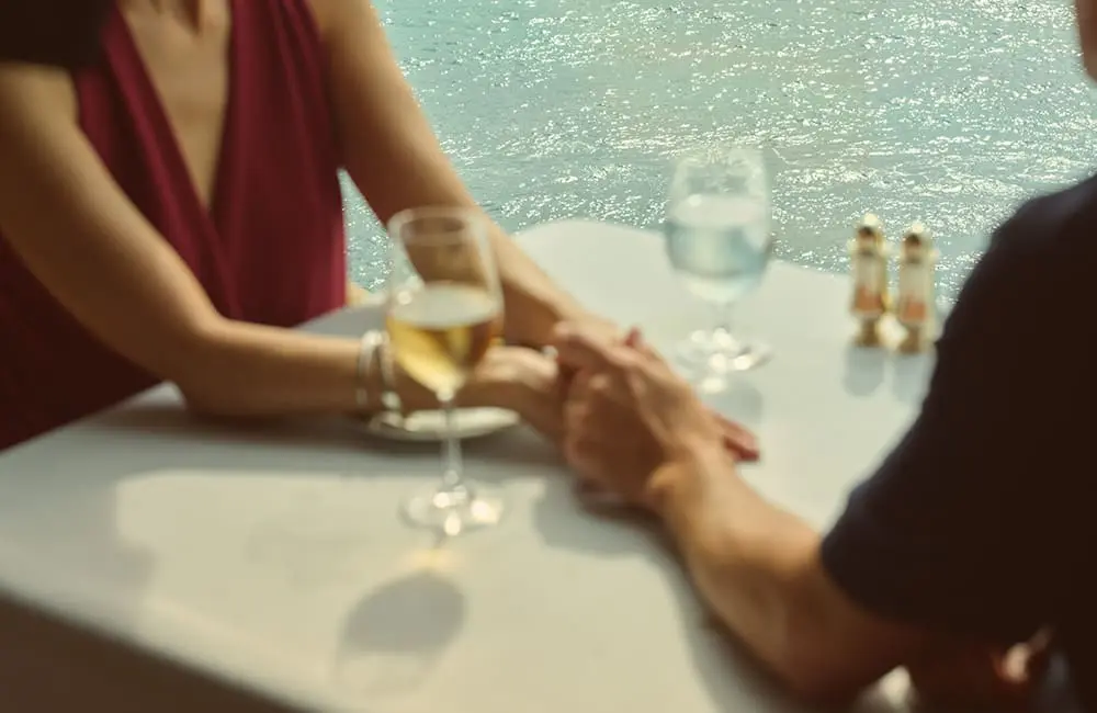 Wake up somewhere extraordinary: Oceania Cruises launches new collection with 50% reduced deposits 5 Couple holding hands on table at Italian-style fine dining at Toscana aboard Oceania Cruises.