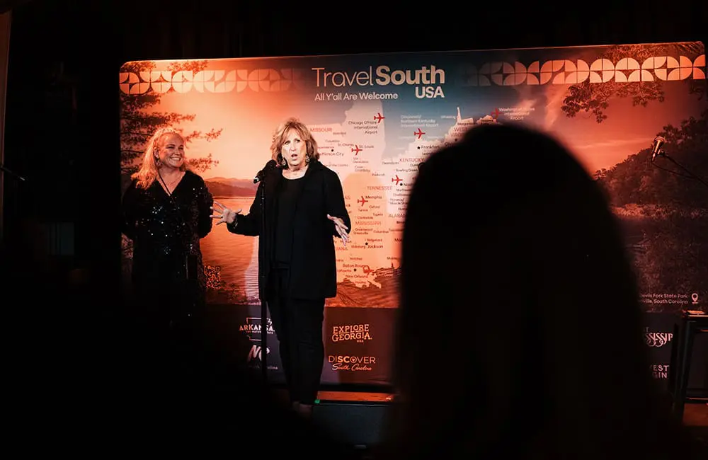Gate 7 Head of Tourism Development & Travel South USA Account Manager Penny Brand with Travel South USA President & CEO Liz Bittner on stage.