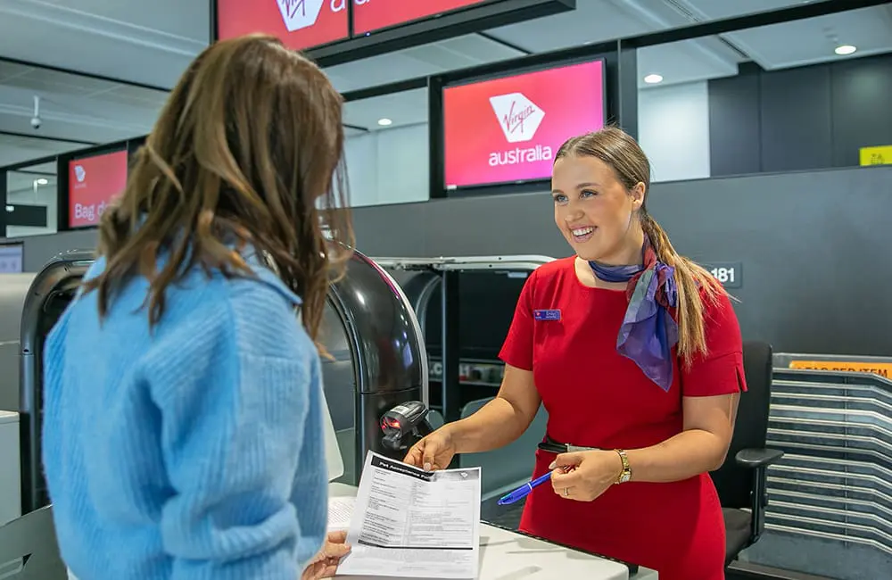 Virgin Australia crew member checks in passenger for Pets in Cabin services start in Adelaide