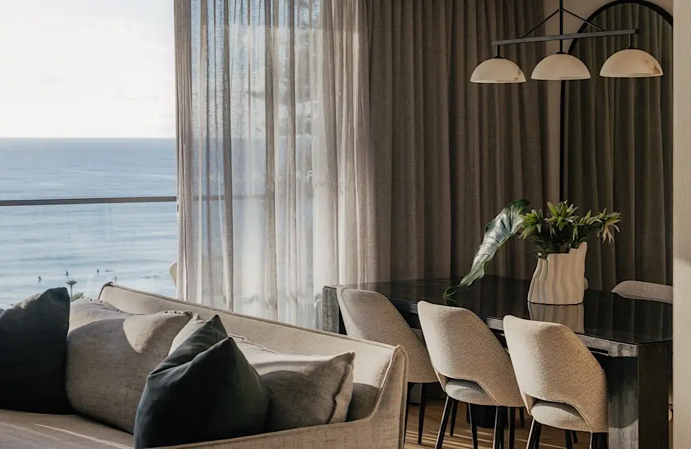A light-filled dining and living space at Elysium Manly, with sweeping views across the coast.