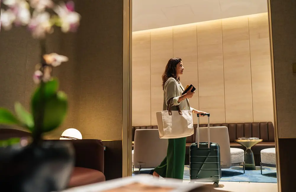 Female passenger wheeling luggage in airport lounge. Image: Sze kiat Koh/iStock