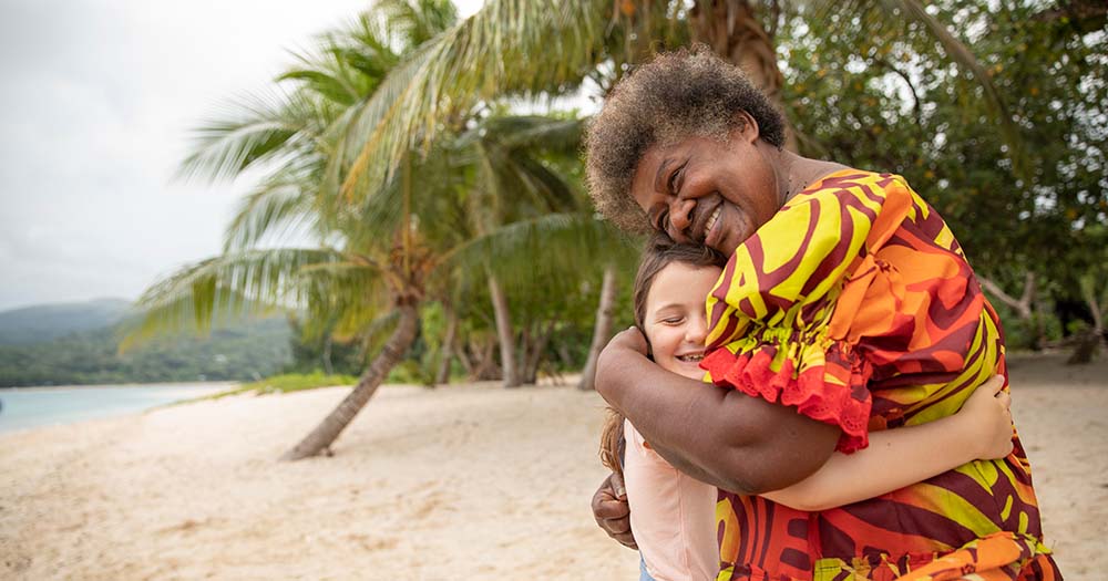 Child and woman hug on Vanuatu beach