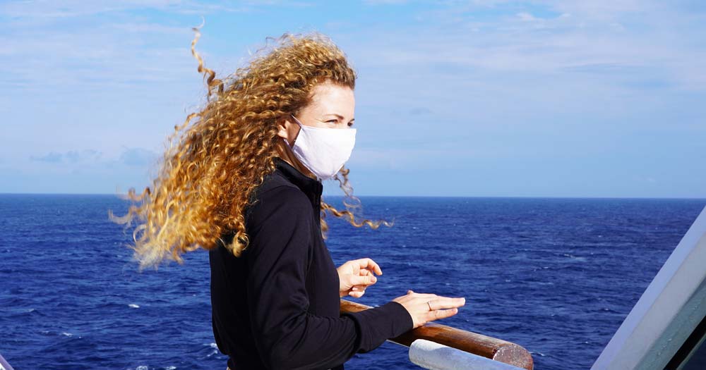 Woman wearing medical face mask on a cruise deck.