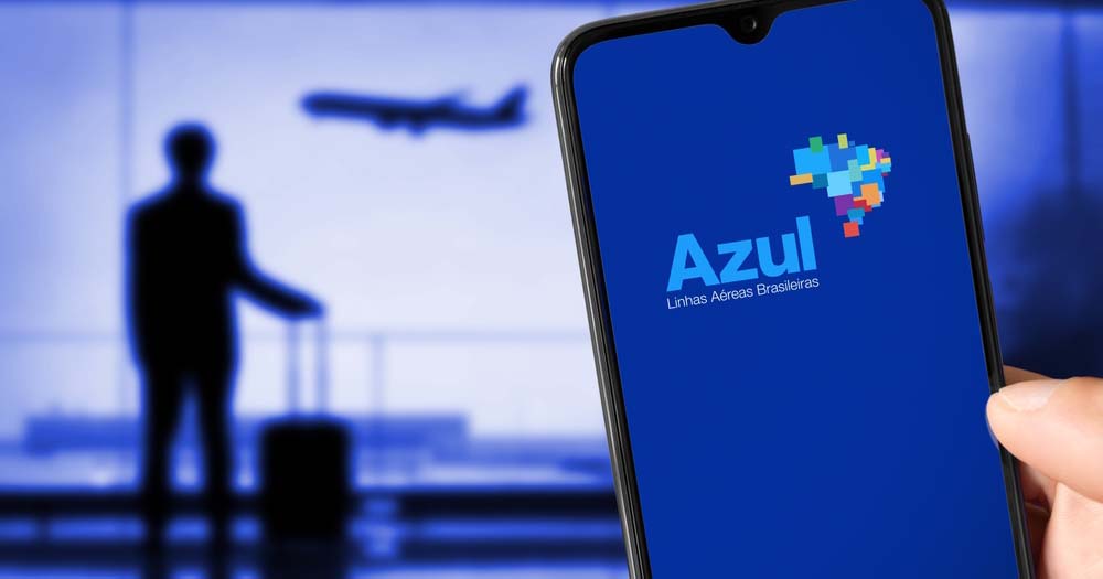 Azul Airlines app on smartphone with traveller and aircraft in background at airport.