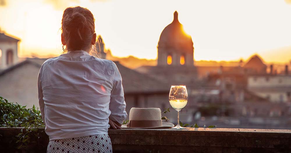 Women on balcony with wine watching sunset in Rome.