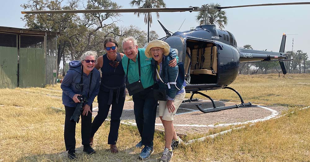 Four people pose outside helicopter in Africa