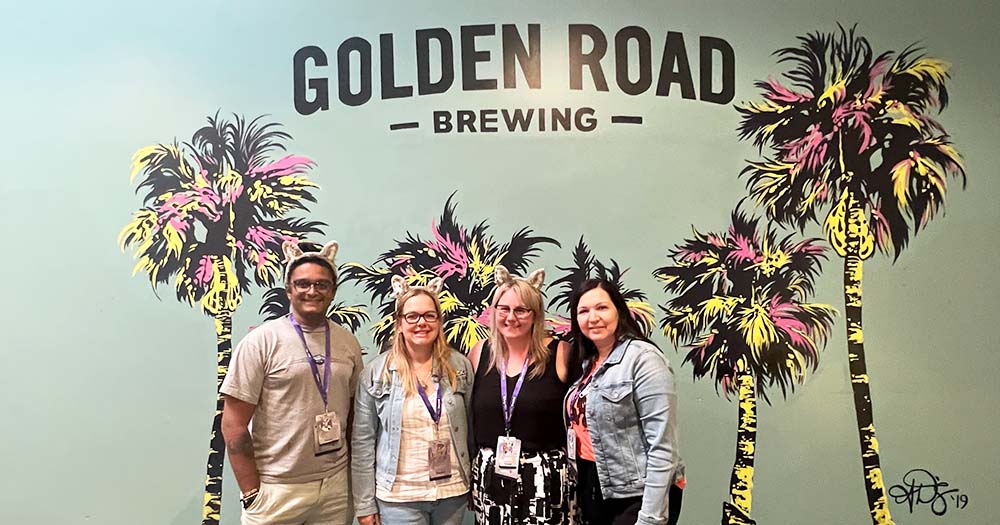 Group of travel agents pose at Golden Road Brewing sign in Anaheim.