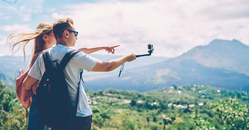 Western tourist couple on Bali mountain with camera stick.