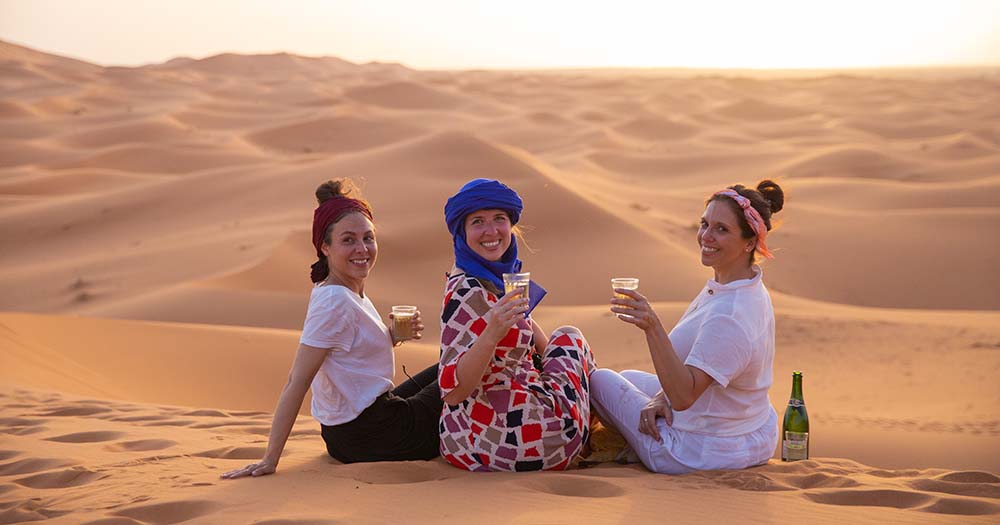 Trois jeunes femmes avec des boissons dans le désert du Sahara, au Maroc.