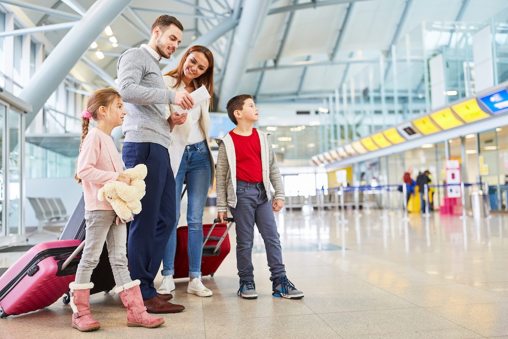 Family and children with luggage in airport terminal fly together on vacation