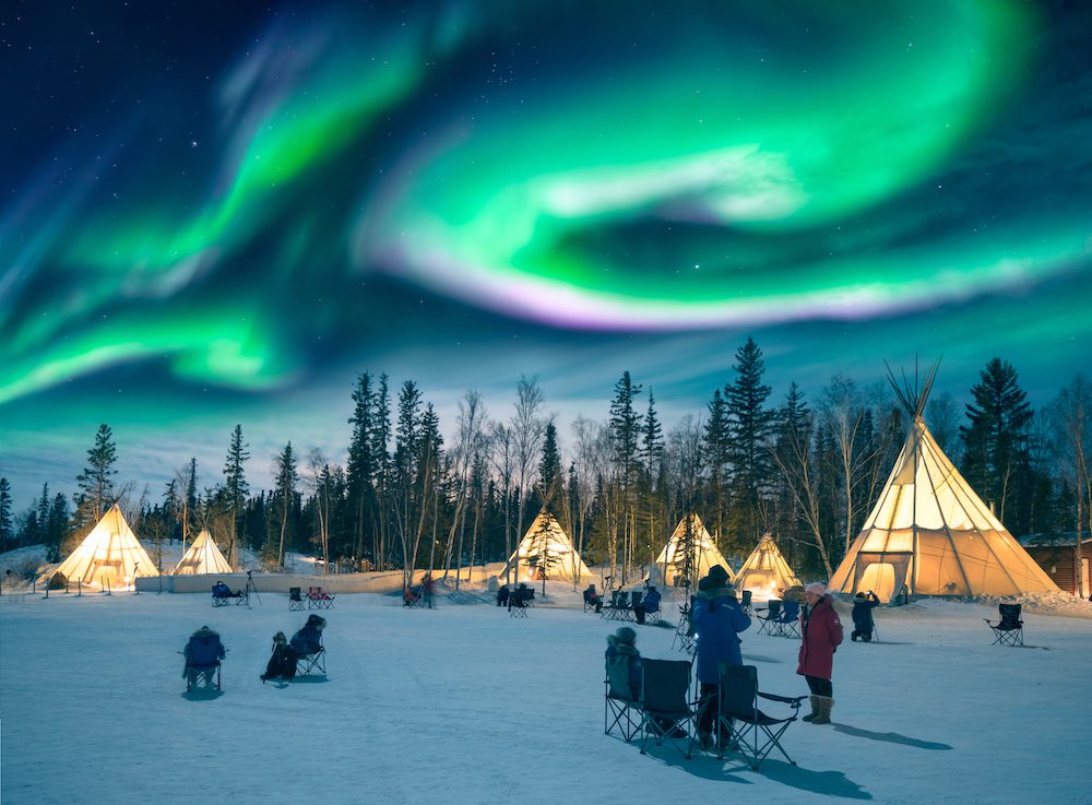 Yellowknife, Canada - March 17 2016 : Amazing northern lights dancing over the tepees at Aurora Village in Yellowknife.