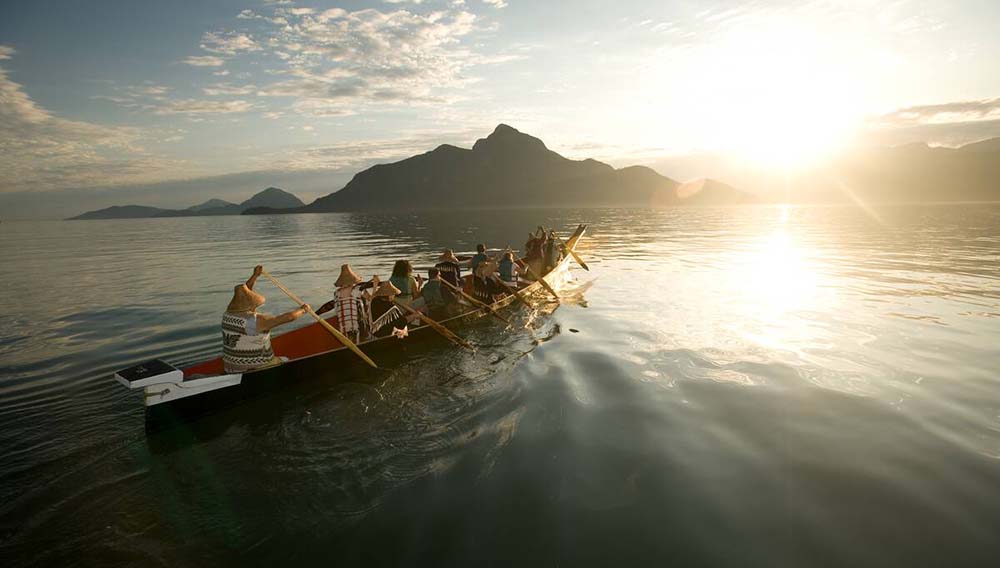 DBC A group with Takaya Tours rowing a traditional First Nations canoe in Howe Sound with mountains in the background Destination BC Patrice Halley
