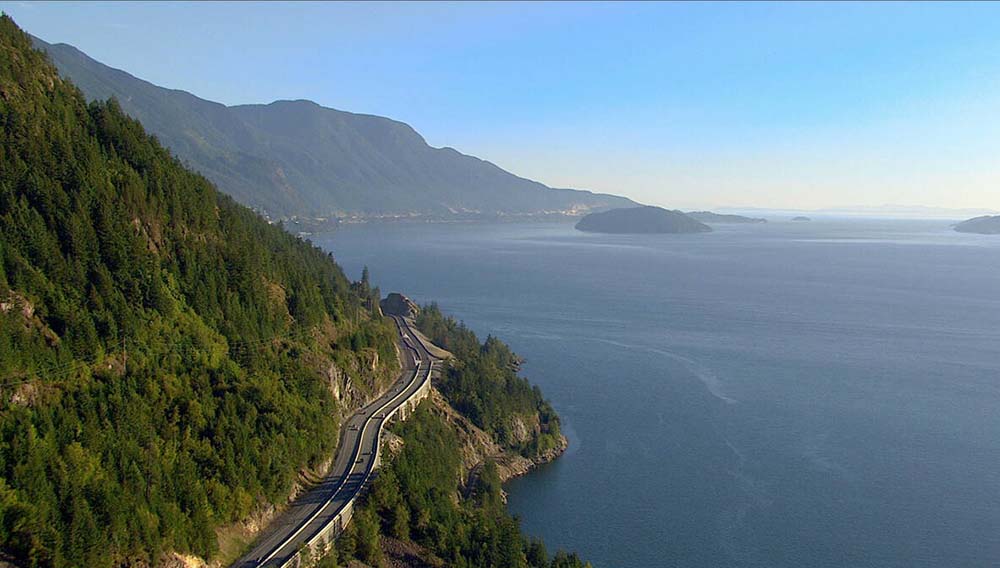 DBC Cars driving the Sea to Sky Highway between Vancouver and Whistler with ocean and mountains in the background DestinationBC