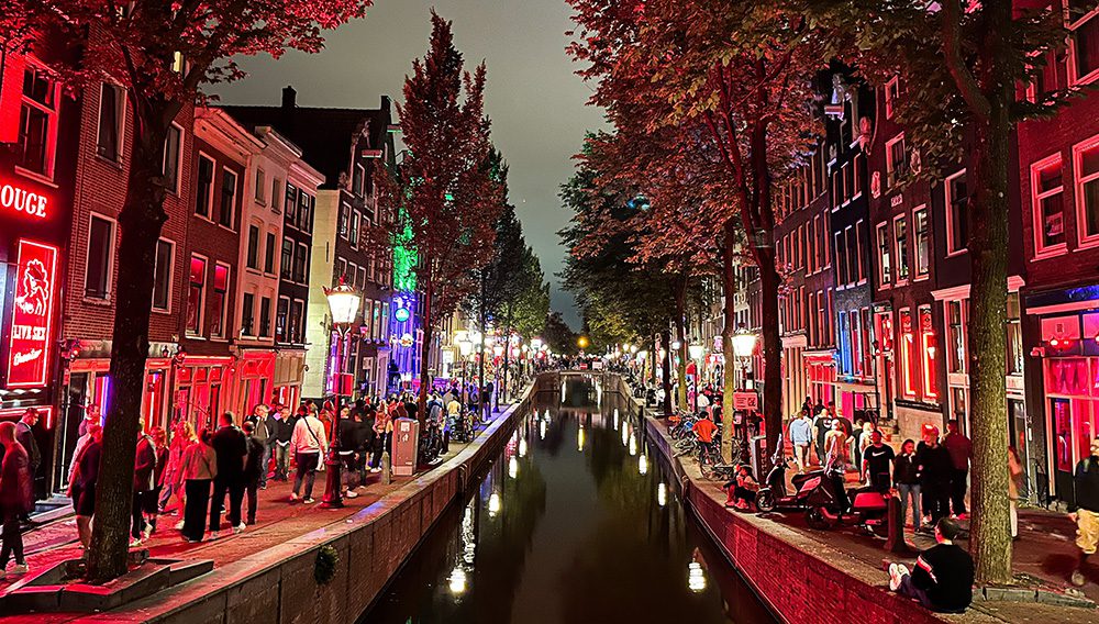 Amsterdam's Red Light District at night with people on the canal.