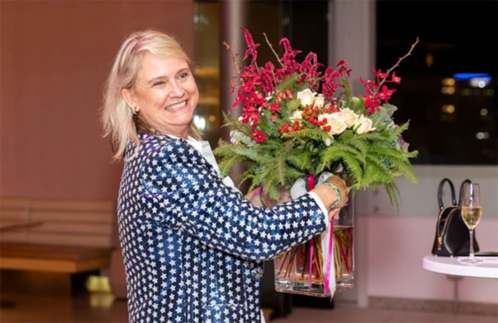 itravel agent Nicole Beasley holding a vase of flowers at a private event.