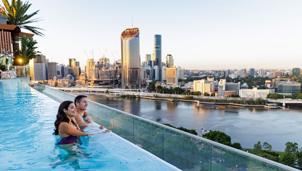 Emporium Hotel South Bank Brisbane couple overlooking the river and city from infinity pool.