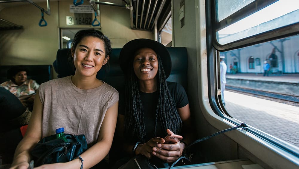 Two smiling female travellers on an Intrepid Travel rail trip to Nuwara Eliya, Sri Lanka.