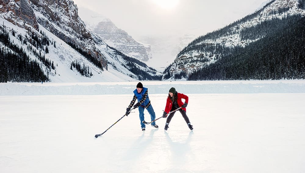 Two people playing ice hockey at Lake Louise, Alberta, Canada. 