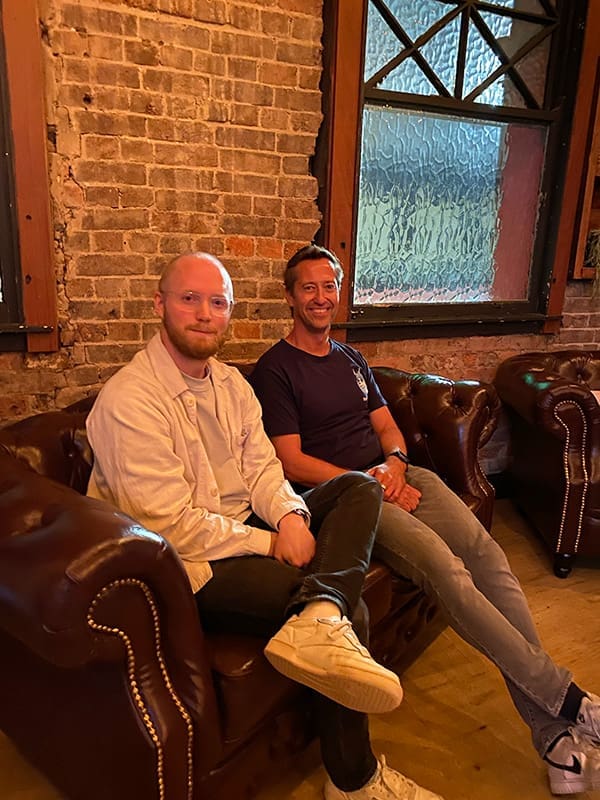 Equator Founder & CEO Edmund Morris & TourRadar Co-Founder & CEO Travis Pittman sitting on couch.