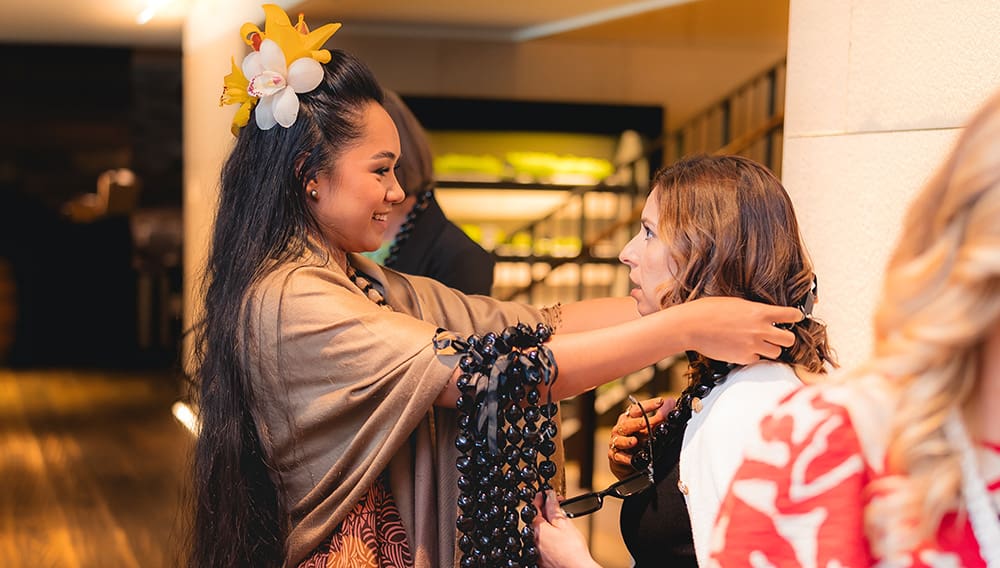 Greeting a guest at event with kukui nut lei.