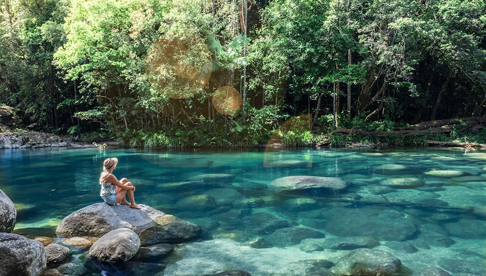 Woman sitting on rock at Mossman Gorge, Daintree National Park, Queensland.