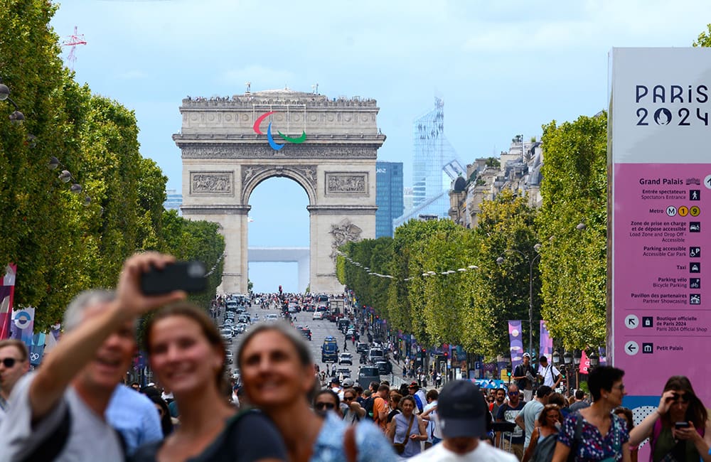 Tourists take selfies on the Champs-Elysee during Paris 2024. Image: Rob Fuller/Shutterstock