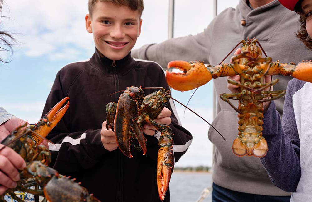 People holding lobsters on Prince Edward Island. Image: Kamil Bialous