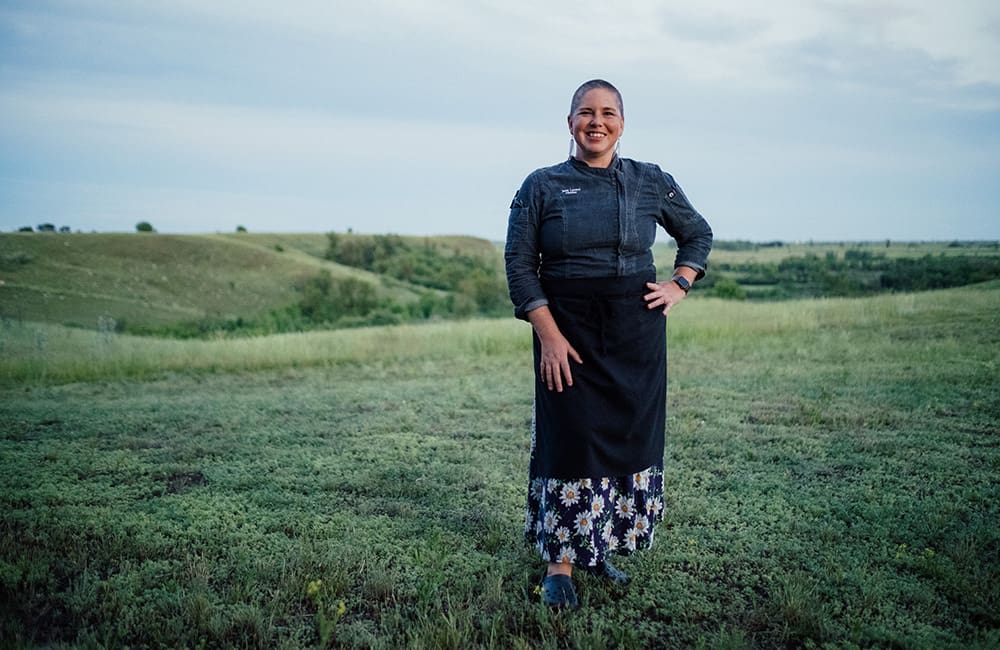 Woman in chef clothes in field at Wanuskewin Heritage Visitor Centre, Saskatchewan. Image: Destination Canada