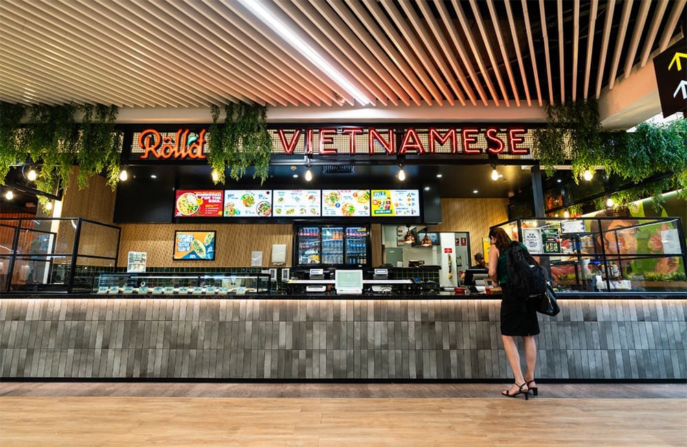 Passenger ordering at Vietnamese counter at Roll'd in Cairns Airport.